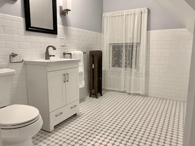 bathroom featuring radiator heating unit, vanity, tile walls, and toilet