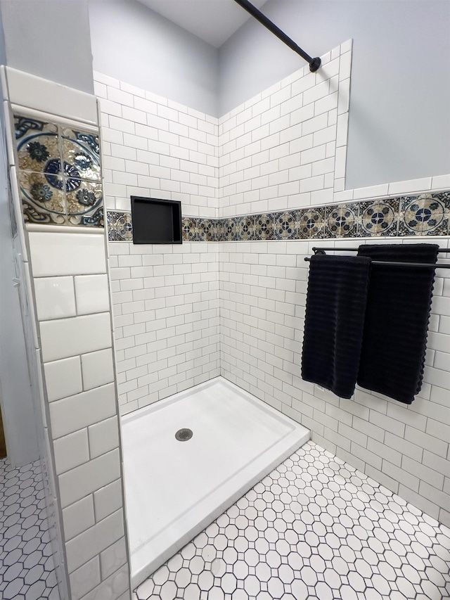 bathroom with a shower, tile patterned flooring, and tile walls