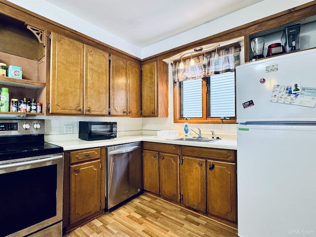 kitchen with tasteful backsplash, sink, stainless steel appliances, and light wood-type flooring