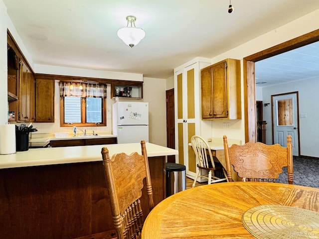 kitchen featuring kitchen peninsula, sink, and white fridge