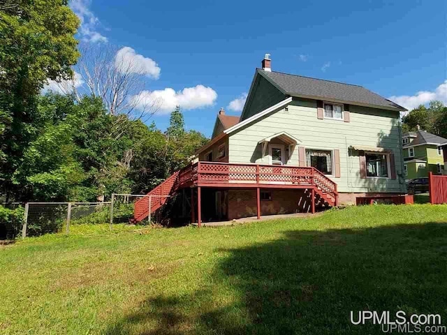 rear view of property featuring a lawn and a deck