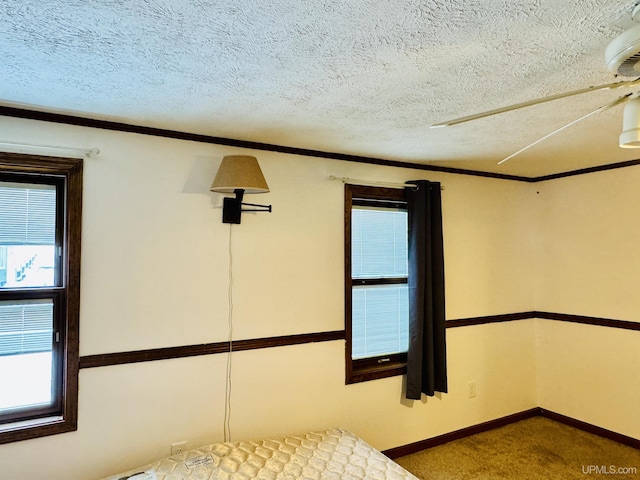 unfurnished bedroom featuring carpet, a textured ceiling, ceiling fan, and ornamental molding