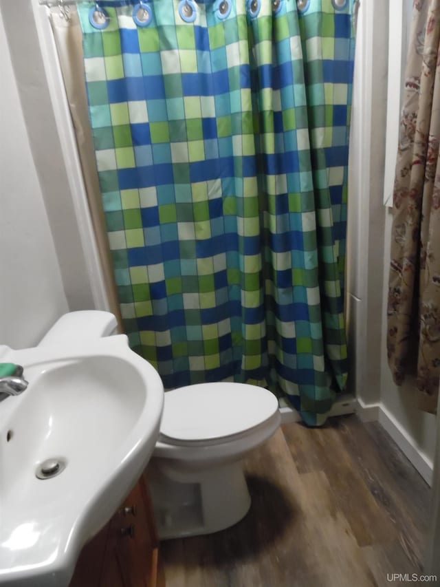 bathroom featuring toilet, wood-type flooring, sink, and walk in shower