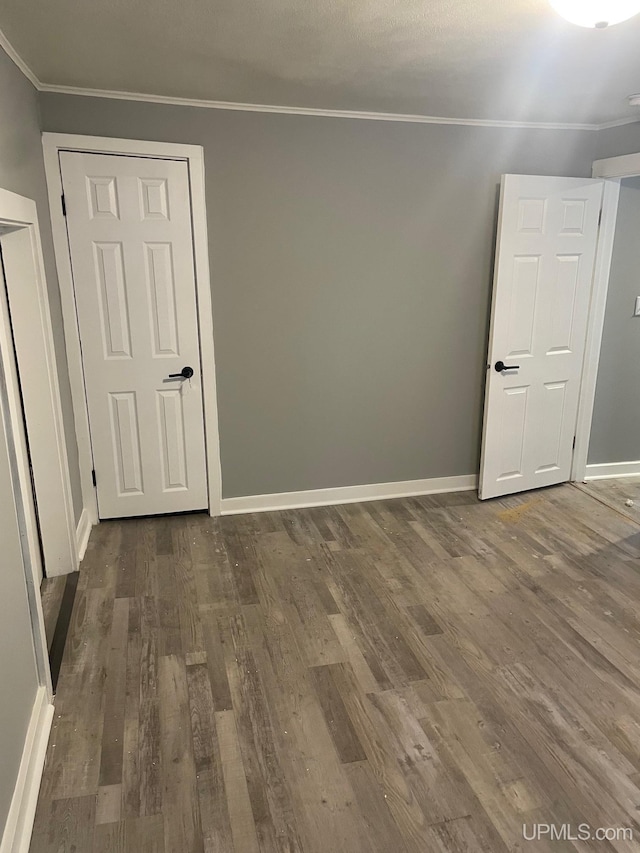 empty room with dark hardwood / wood-style flooring and crown molding