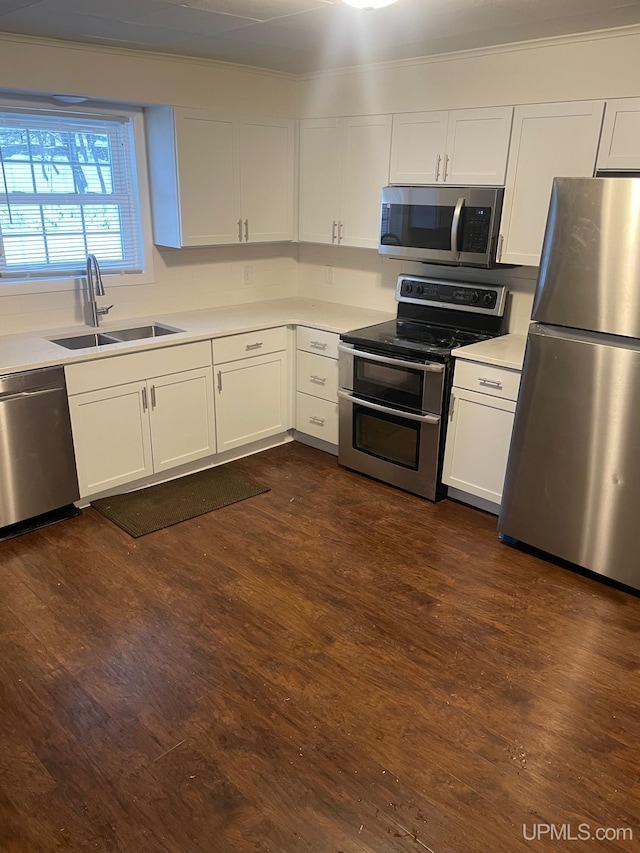 kitchen featuring white cabinetry, sink, dark hardwood / wood-style floors, appliances with stainless steel finishes, and ornamental molding