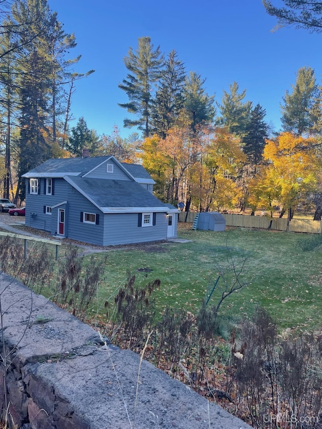 view of side of home with a lawn and a storage unit