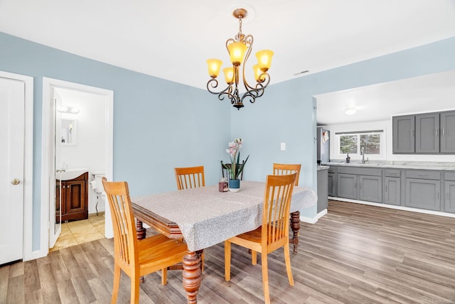 dining room with sink, a notable chandelier, and light wood-type flooring