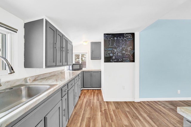 kitchen featuring gray cabinetry, light wood-type flooring, and sink