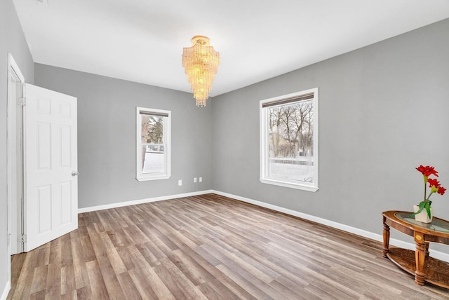 empty room featuring light hardwood / wood-style flooring and an inviting chandelier