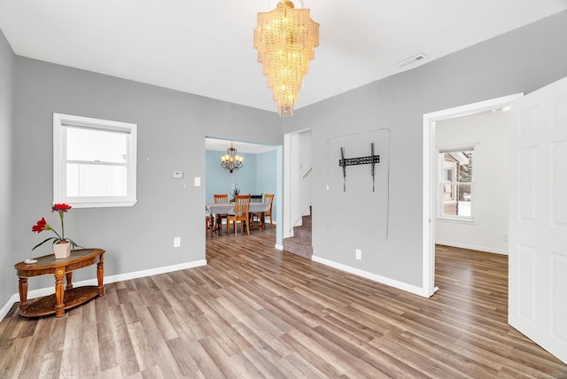 unfurnished room with a notable chandelier and hardwood / wood-style flooring