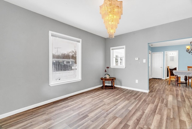 spare room with light hardwood / wood-style flooring and an inviting chandelier