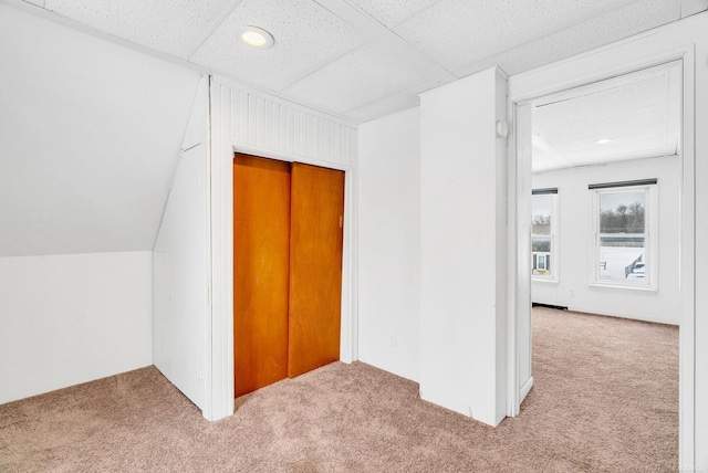 hallway with light carpet, a paneled ceiling, and vaulted ceiling