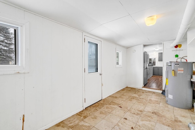 interior space with electric water heater and wood walls