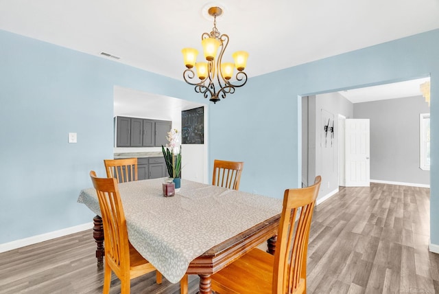 dining space with hardwood / wood-style floors and a chandelier