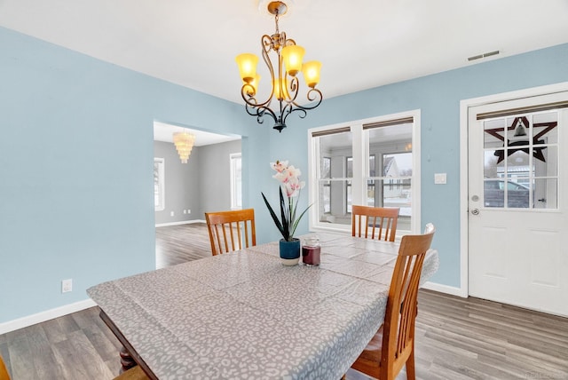 dining space featuring wood-type flooring, an inviting chandelier, and plenty of natural light