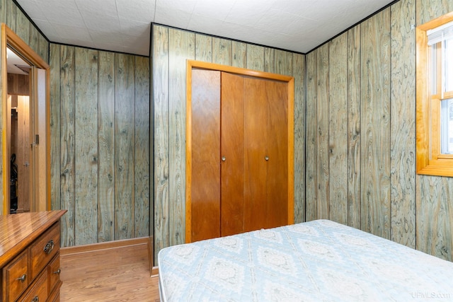 bedroom with wooden walls, a closet, and wood finished floors