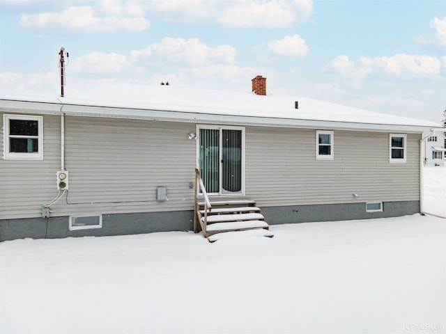 snow covered property featuring entry steps and a chimney