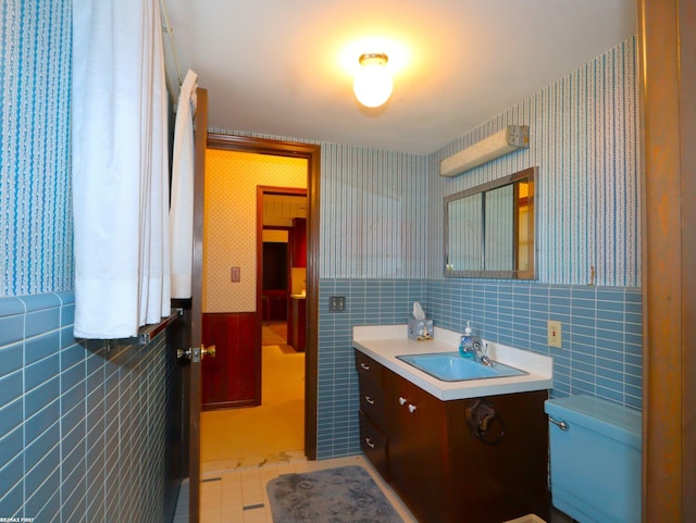 bathroom with toilet, vanity, tile patterned floors, and tile walls