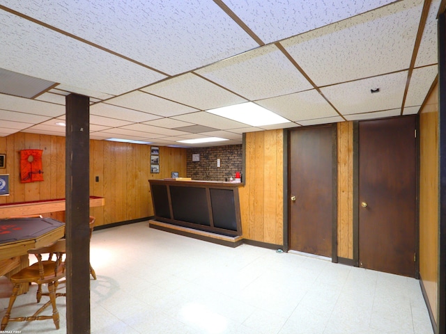 basement with a paneled ceiling and wood walls