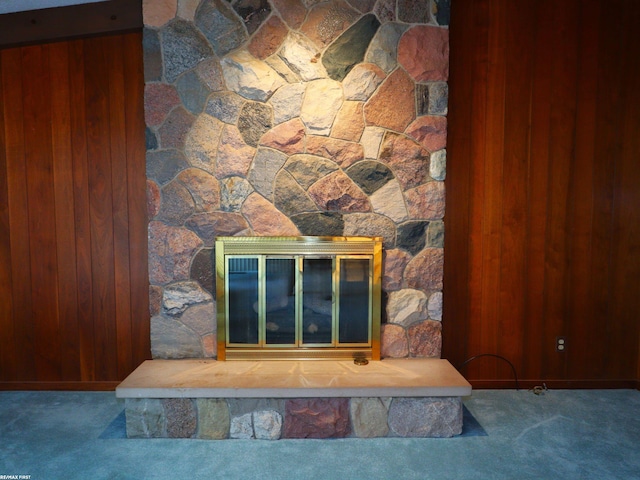 interior details with carpet, a stone fireplace, and wooden walls