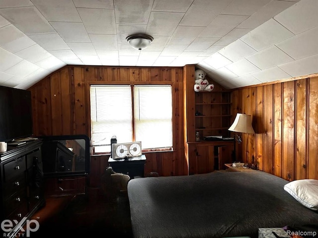 bedroom featuring wooden walls and vaulted ceiling