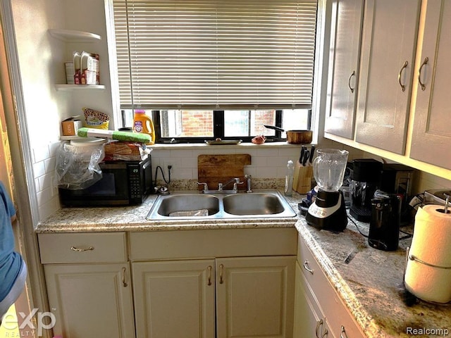 kitchen featuring cream cabinets, backsplash, and sink