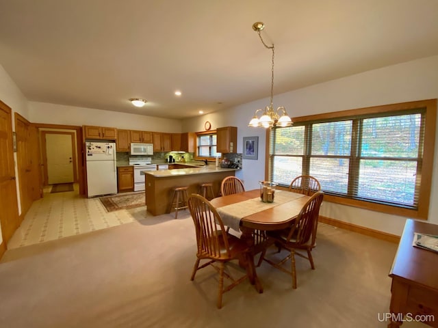 carpeted dining space with a healthy amount of sunlight and an inviting chandelier