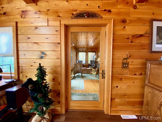 doorway with dark hardwood / wood-style flooring, a healthy amount of sunlight, and wood walls