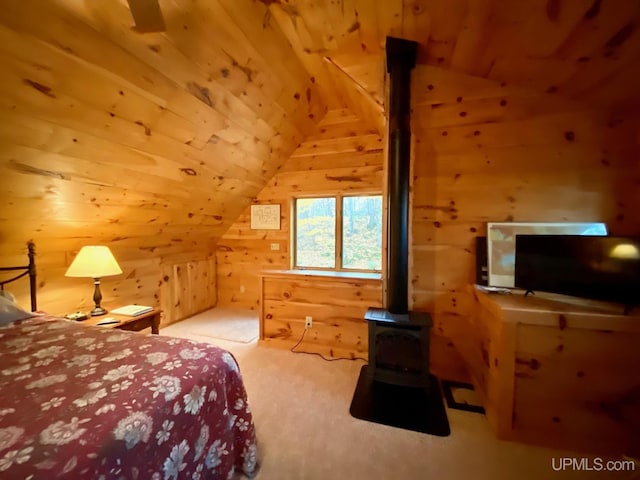 bedroom with wooden walls, a wood stove, and lofted ceiling