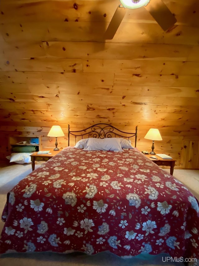 bedroom featuring ceiling fan, wooden walls, and carpet floors