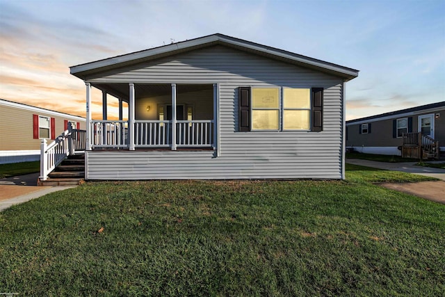 manufactured / mobile home featuring covered porch and a lawn