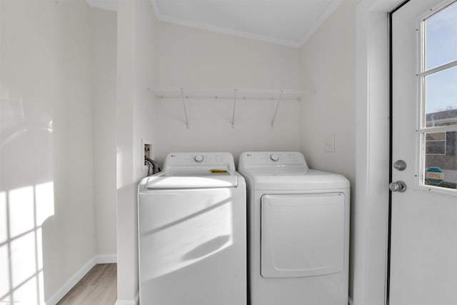 laundry area with washer and clothes dryer, light wood-type flooring, and ornamental molding