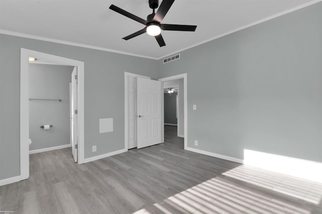 unfurnished bedroom with a walk in closet, ceiling fan, ornamental molding, and light wood-type flooring