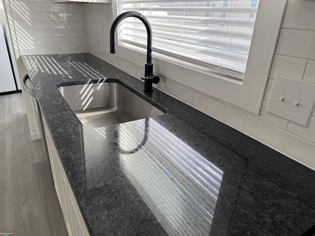 room details featuring white cabinets, dark stone countertops, and sink