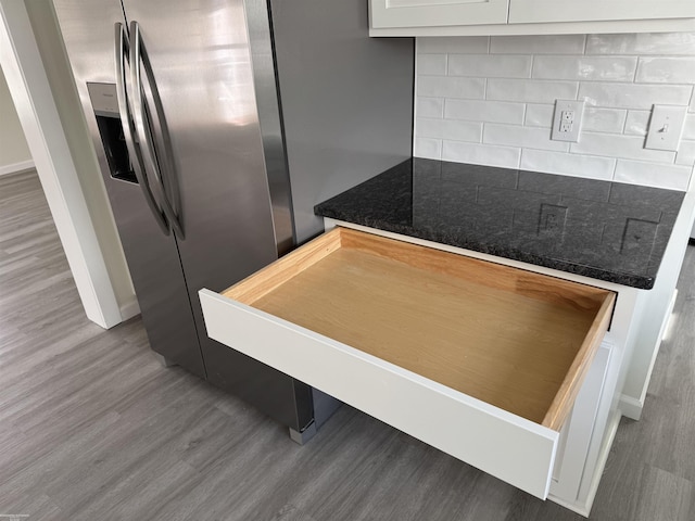 kitchen with stainless steel refrigerator with ice dispenser, wood-type flooring, decorative backsplash, and white cabinetry