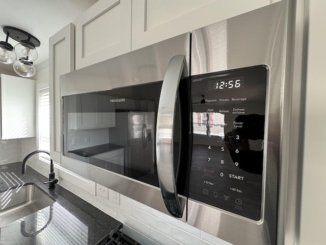 interior details with decorative backsplash, white cabinetry, and sink