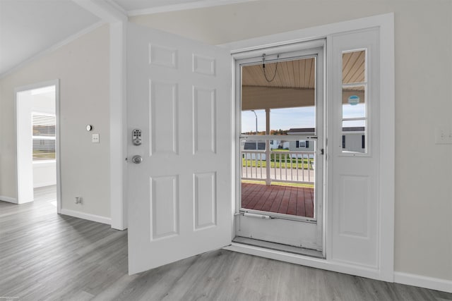 entryway with light hardwood / wood-style floors, crown molding, and vaulted ceiling