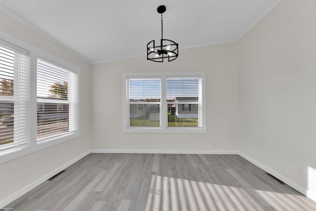 unfurnished dining area with an inviting chandelier, ornamental molding, lofted ceiling, and light wood-type flooring