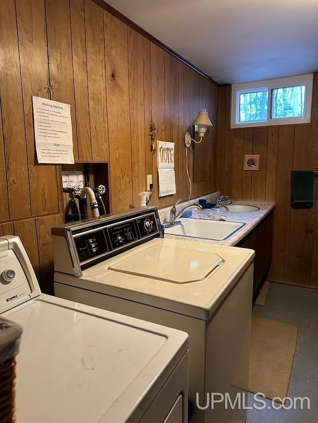 laundry room with cabinets, sink, washing machine and dryer, and wood walls