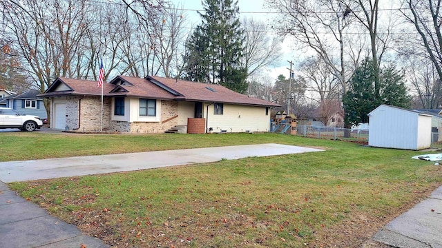 view of front of house featuring a garage, a front lawn, and a storage shed