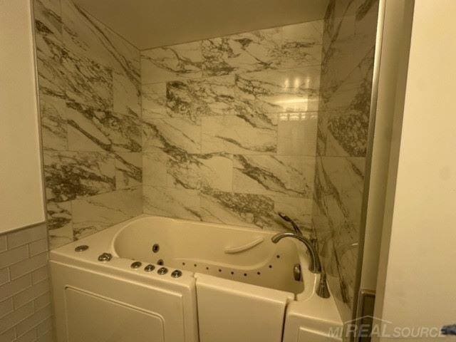 bathroom with a bath and tile walls