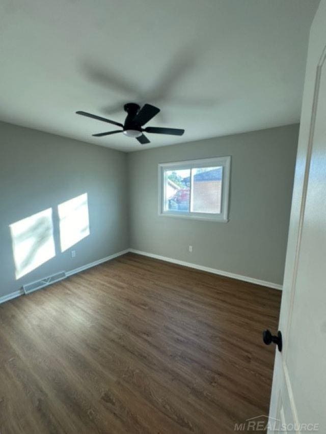 unfurnished room featuring ceiling fan and dark wood-type flooring