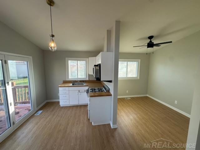 kitchen with white cabinets, wood counters, pendant lighting, and plenty of natural light