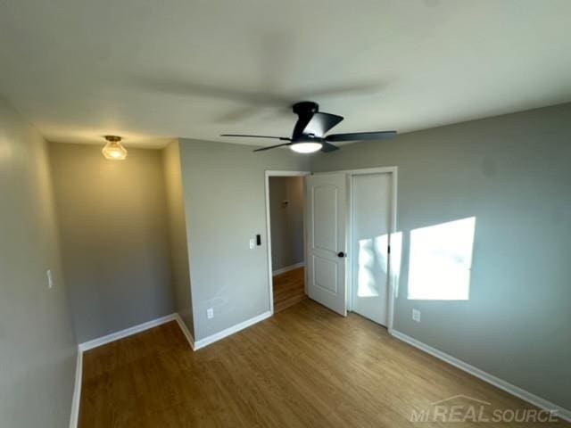 unfurnished bedroom featuring ceiling fan, light hardwood / wood-style floors, and a closet