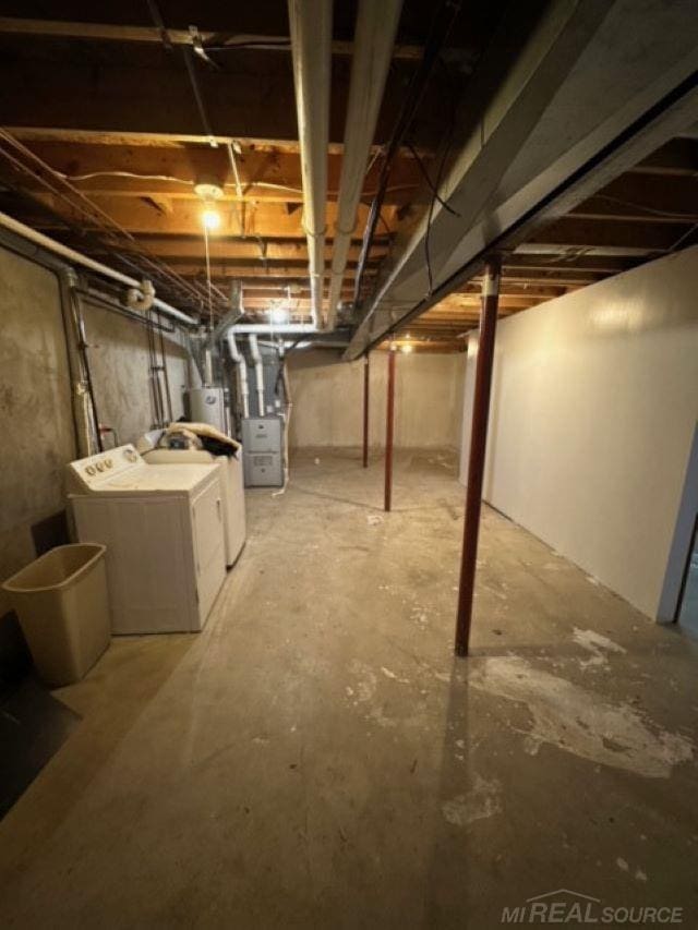 basement with heating unit, washing machine and dryer, and water heater