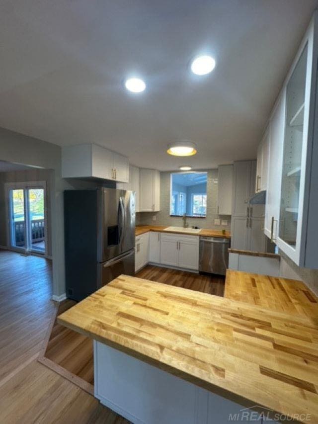 kitchen with kitchen peninsula, white cabinetry, a wealth of natural light, and appliances with stainless steel finishes