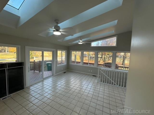 unfurnished sunroom featuring ceiling fan and lofted ceiling with skylight