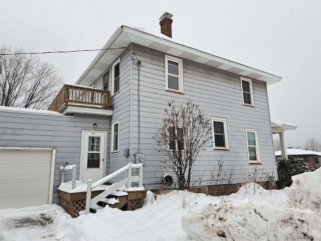 snow covered property with a balcony and a garage