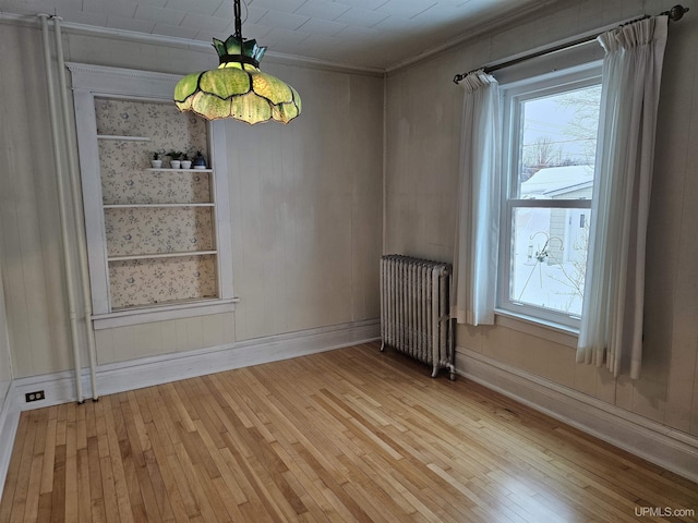 unfurnished dining area featuring light hardwood / wood-style floors, ornamental molding, and radiator