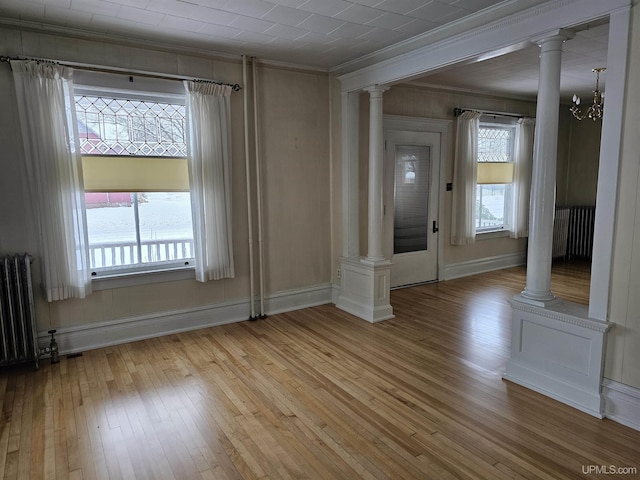 interior space with light hardwood / wood-style floors, an inviting chandelier, radiator, and ornamental molding